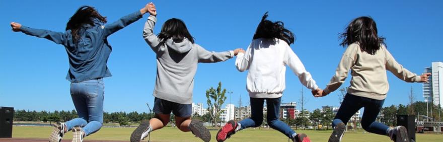Ragazze che saltano per mano in un parco per bandi pon comune di bologna adolescenti e giovani