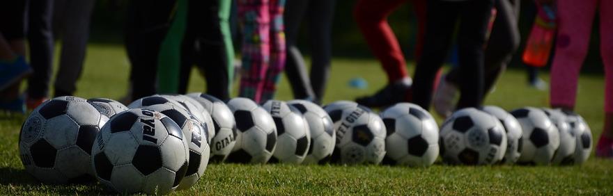Foto di palloni da calcio su campo sportivo con piedi di calciatori